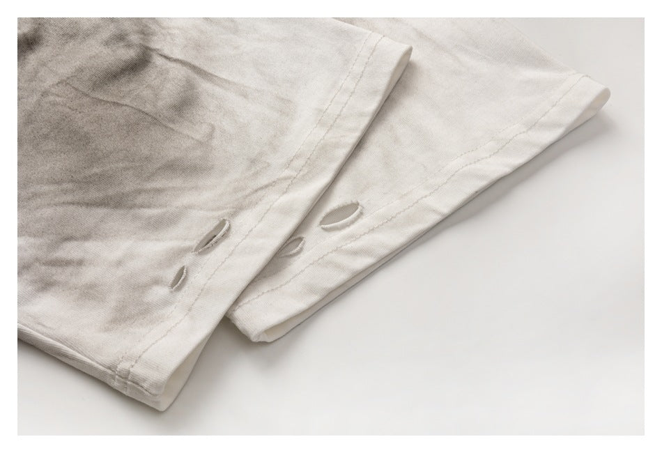 Close-up of pale gray garment hems with several small cutout details and visible stitching.