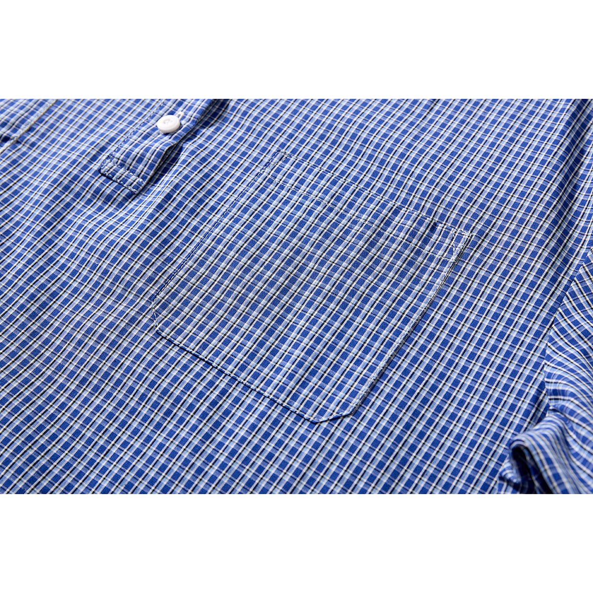 Close-up of a chest pocket and white button on a blue plaid shirt.