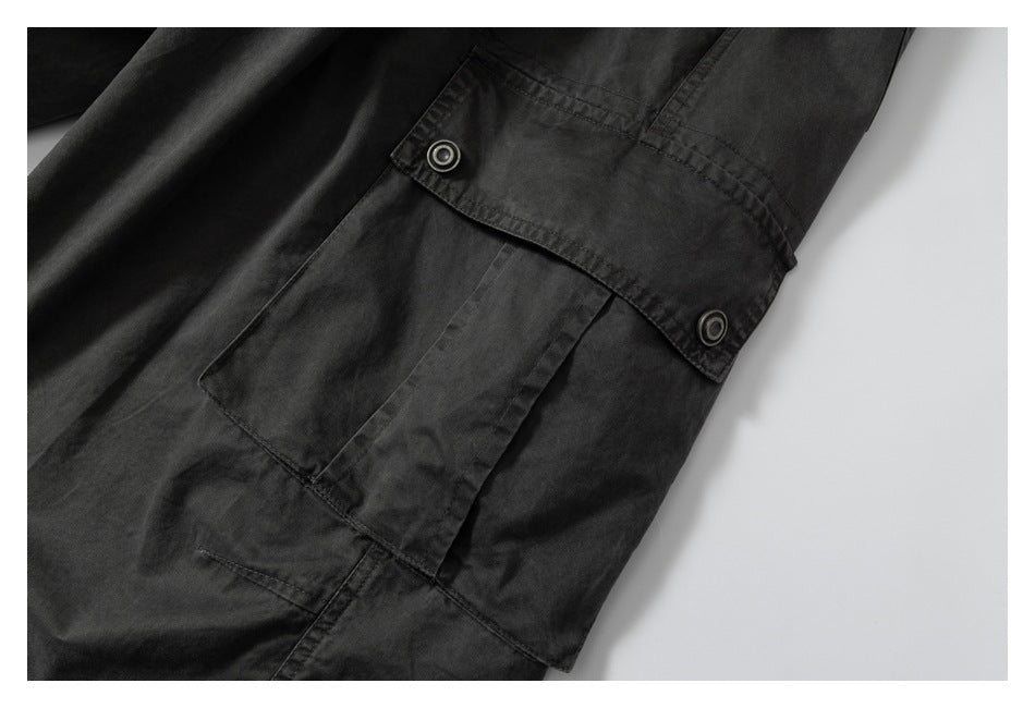 Close-up of a charcoal cargo pants pocket with a buttoned flap and visible stitching.
