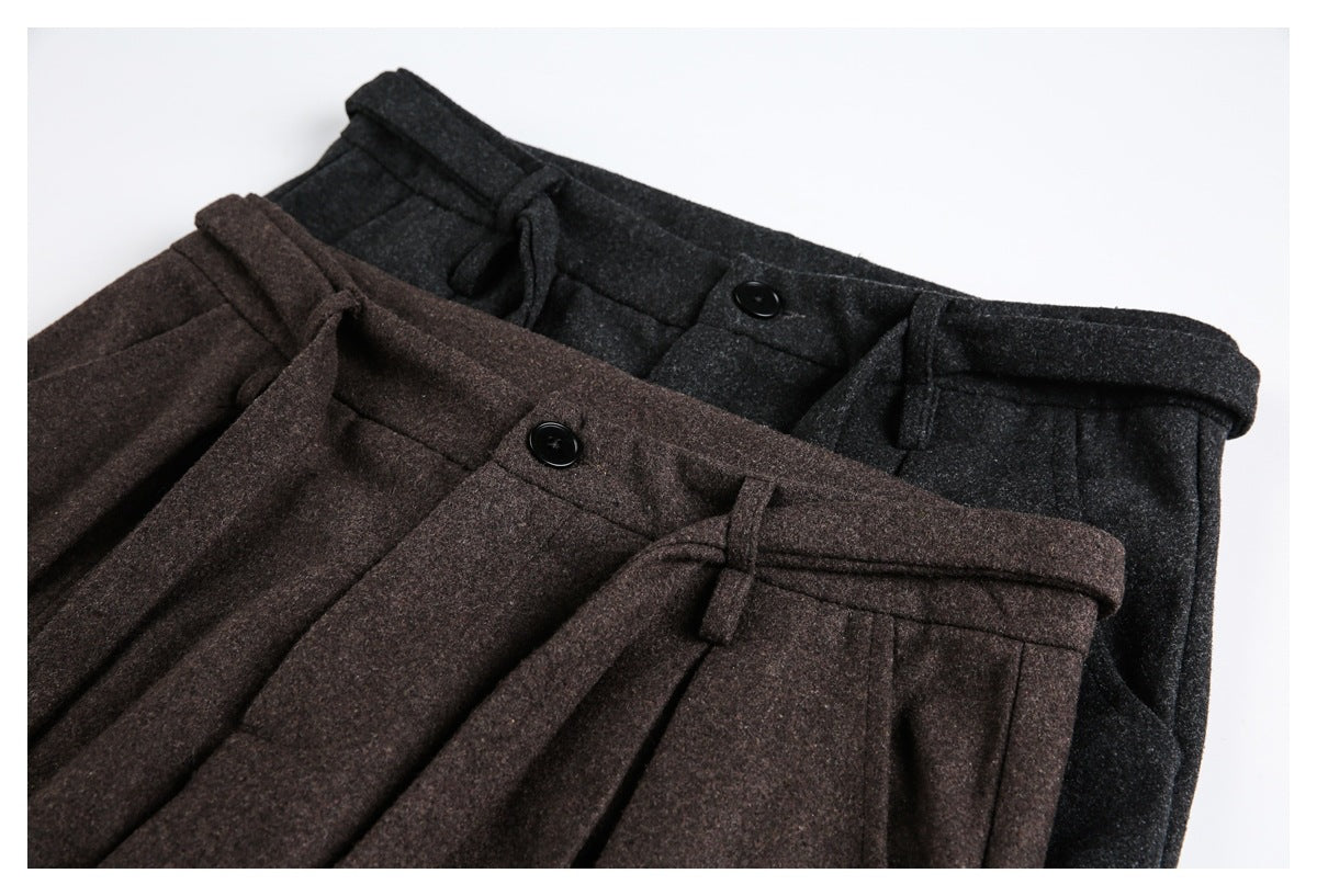 Close-up of brown and charcoal trousers showing their waistbands, buttons, belt loops, and pleats.