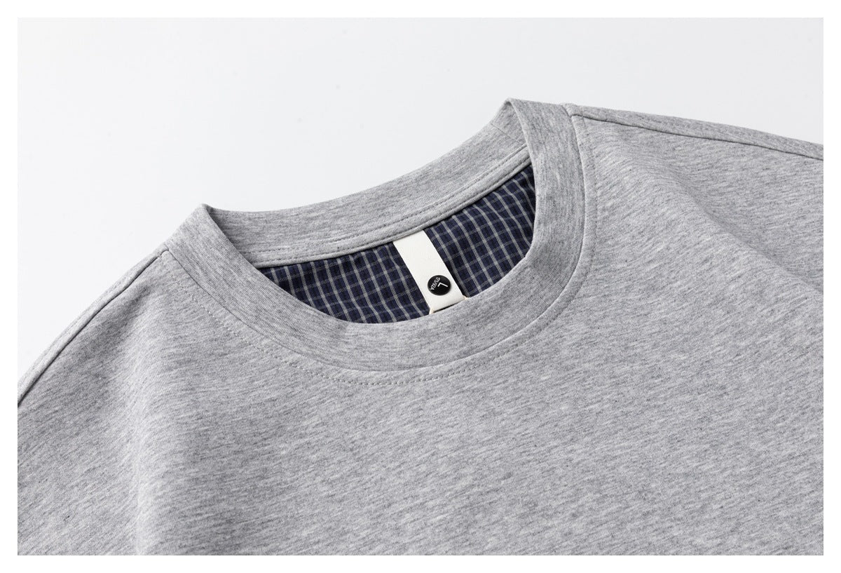 Close-up of a gray T-shirt crew neck with dark check-pattern inner facing and a small size label.