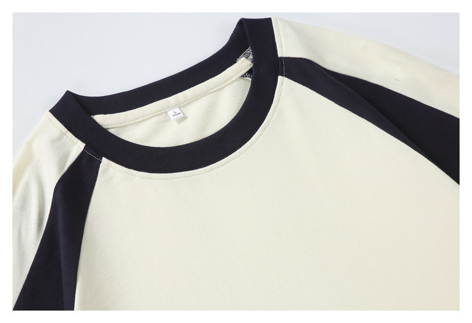 Close-up of the cream T-shirt's black crew neck and contrasting raglan shoulder panels.