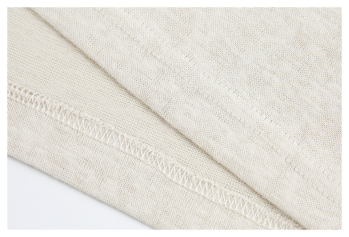 Close-up of cream knit fabric showing an interior overlocked seam and stitching.