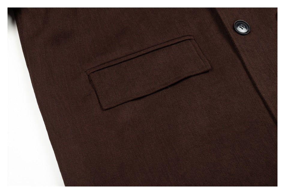Close-up of a dark brown garment showing a rectangular welt pocket and one black button.