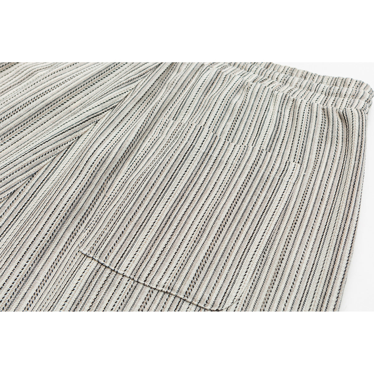 Close-up of a rectangular patch pocket on cream trousers with fine black vertical stripes.