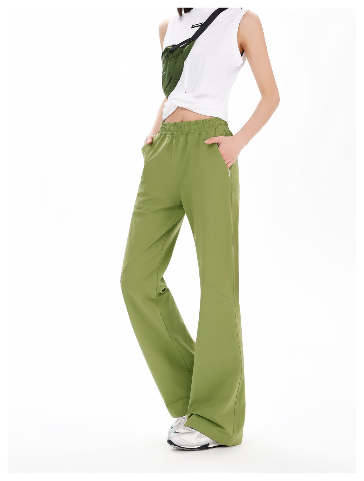 Angled view of olive-green wide-leg pants with an elastic waistband and side pockets, worn by a model.