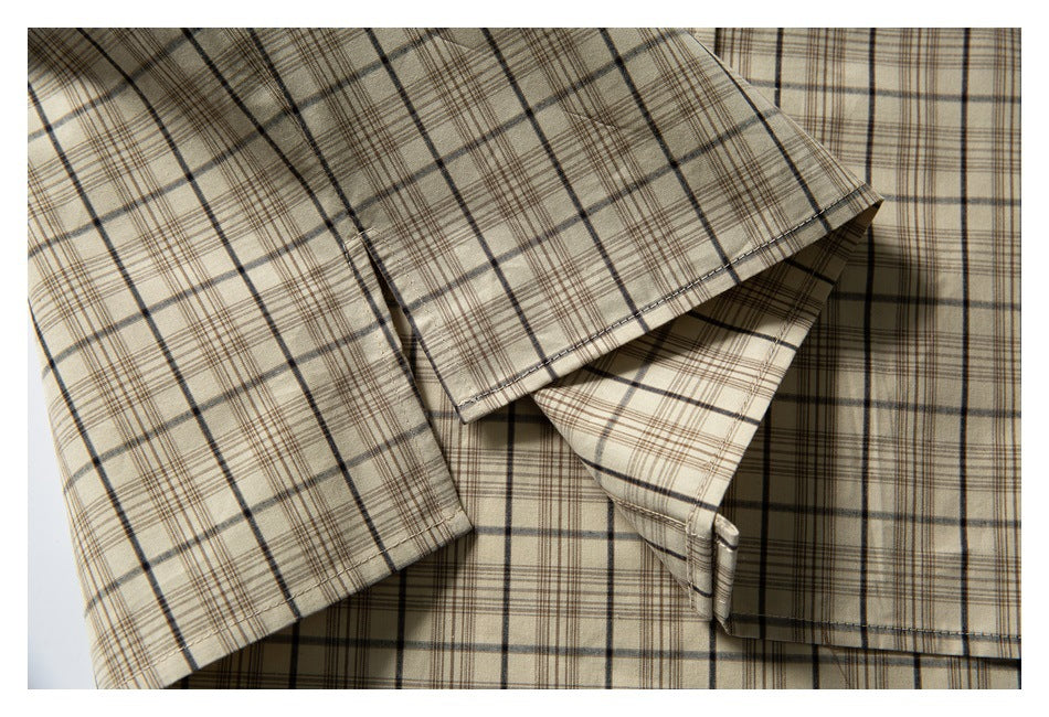 Close-up of the beige plaid shirt's sleeve and cuff laid over the body.