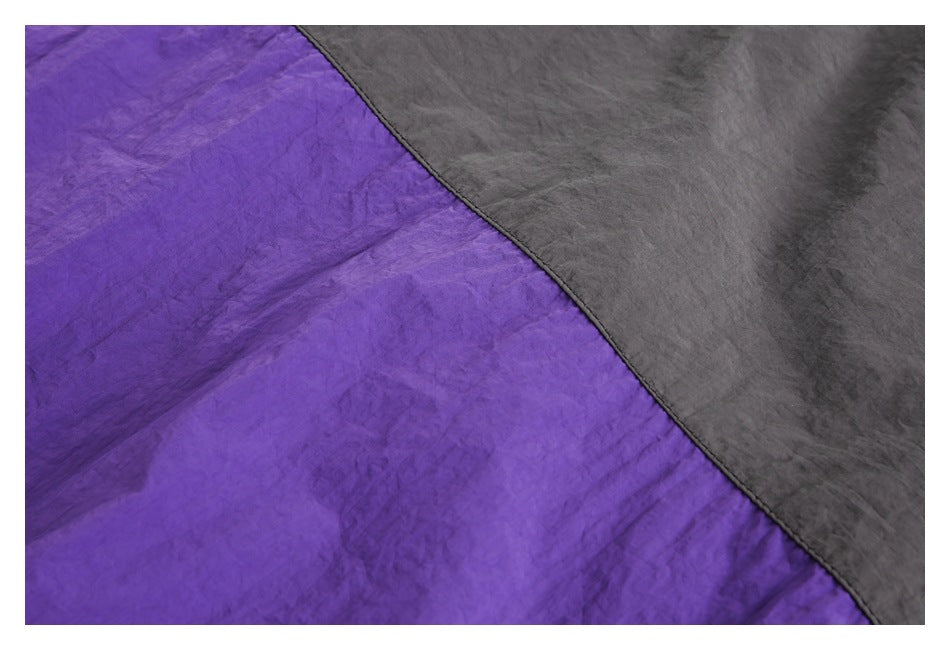 Close-up of purple and charcoal gray fabric panels meeting at a curved stitched seam.