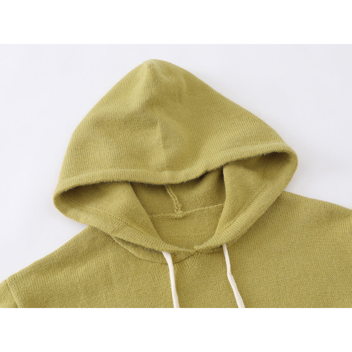 Close-up of a mustard-yellow knitted hoodie hood with white drawstrings.