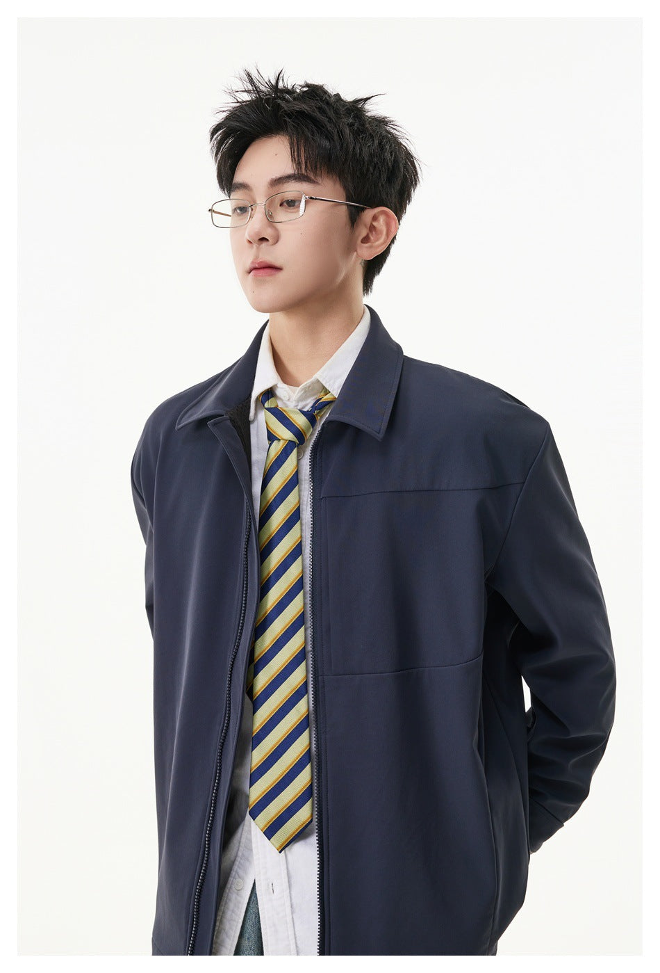 Close view of a model wearing a navy collared zip-front jacket over a white shirt and striped tie.