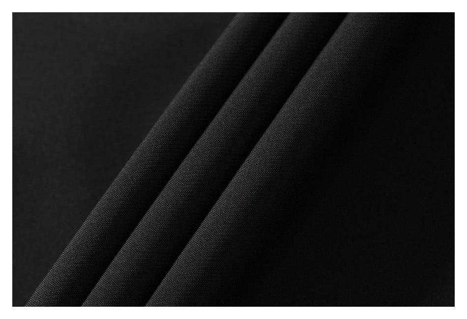 Close-up of black garment fabric draped in folds, showing its fine surface texture.