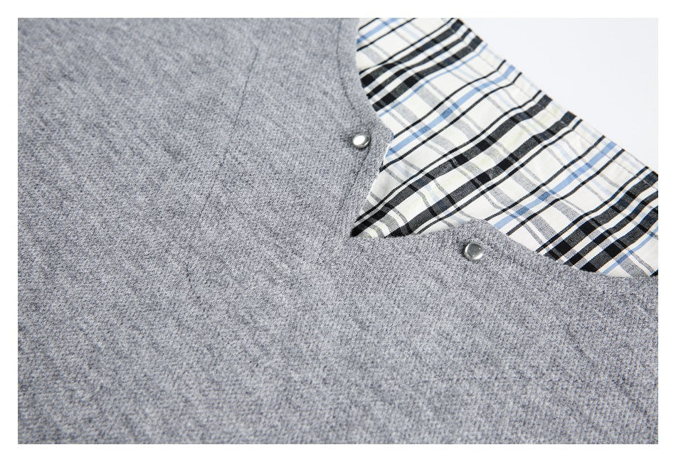 Angled close-up of the gray garment neckline, metal snaps, and exposed black, white, and blue plaid lining.