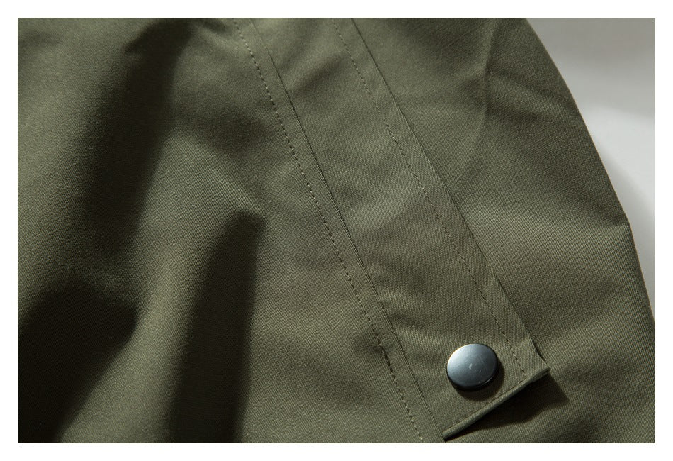 Close-up of an olive jacket sleeve seam and snap-fastened cuff.
