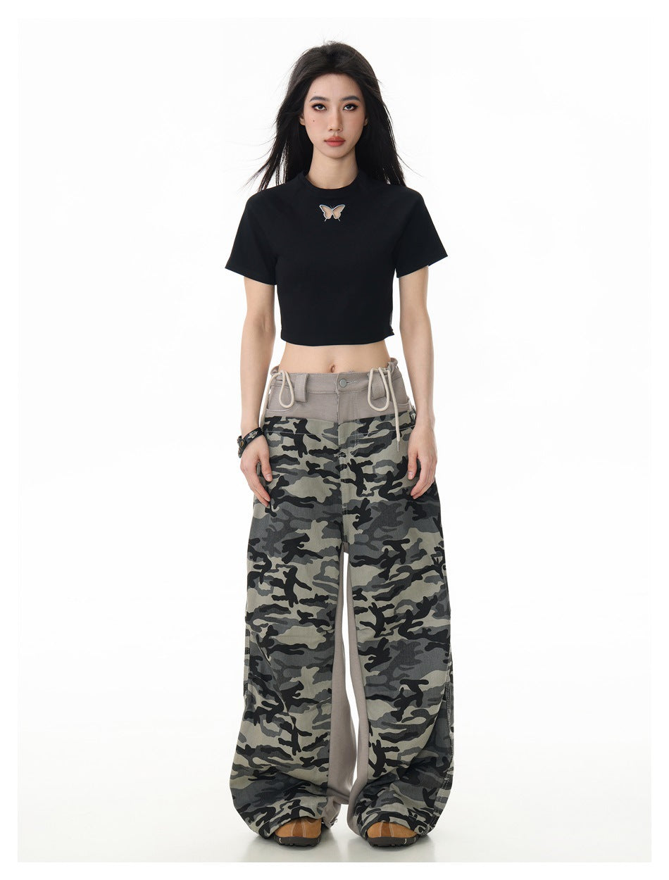 Woman wearing a black cropped butterfly T-shirt with wide camouflage pants, full-length front view