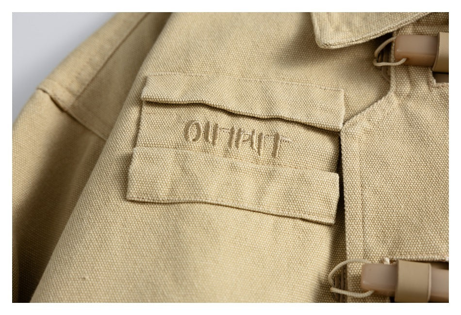 Close-up of a beige woven flap with stitched lettering and tan plastic toggles.