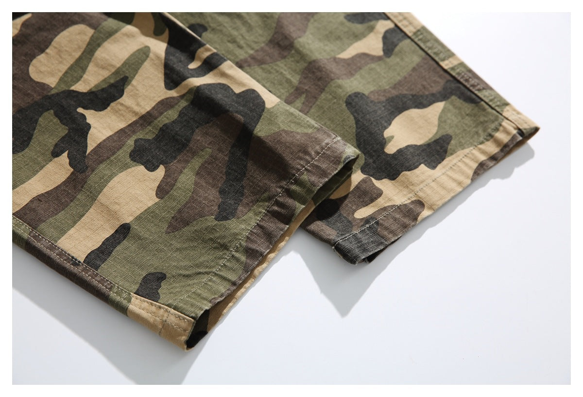 Close-up of the stitched hems on olive, tan, brown, and black camouflage trousers.