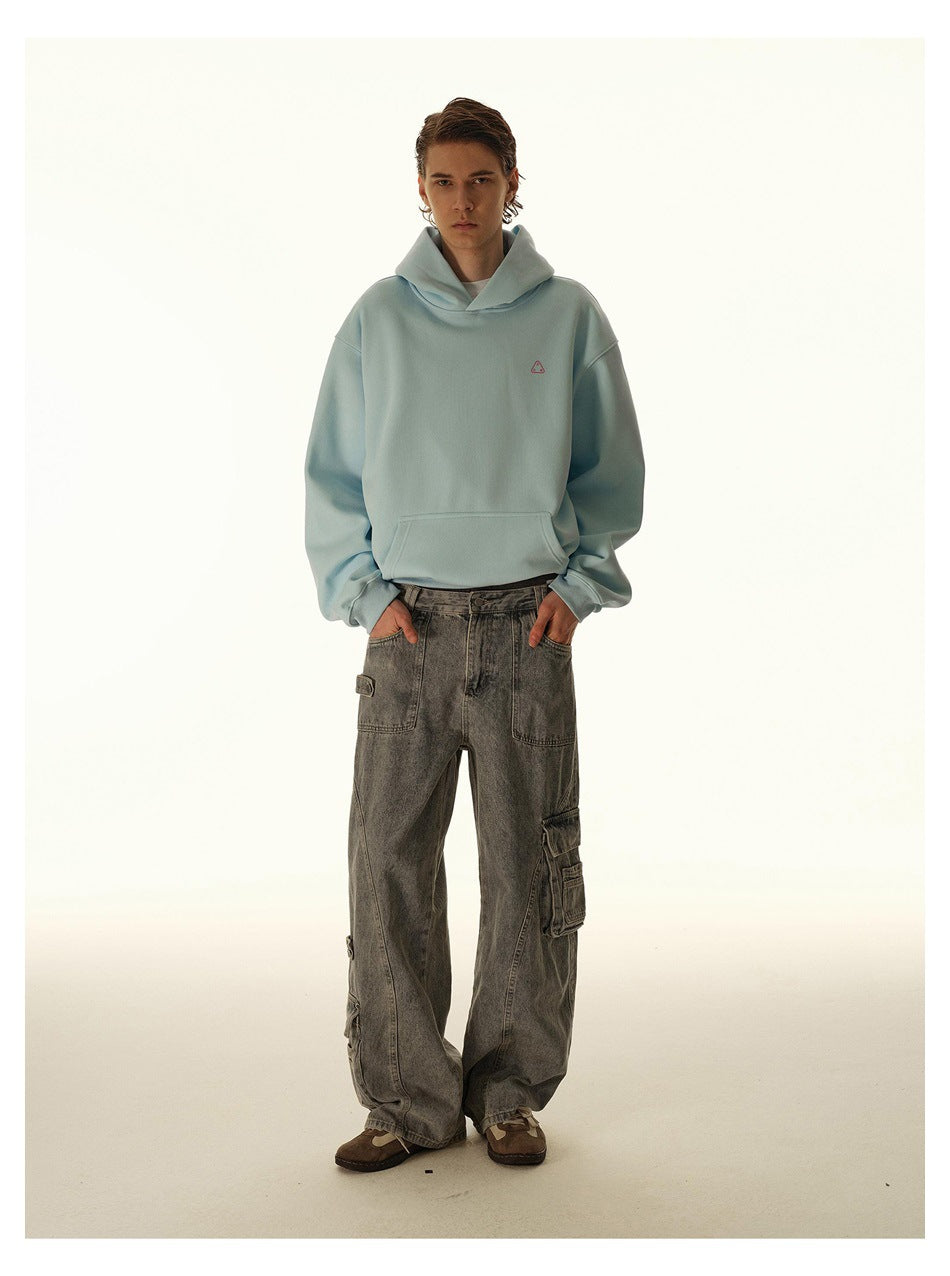 Model wearing a pale blue oversized hoodie with a small chest graphic and loose gray cargo jeans, front view.