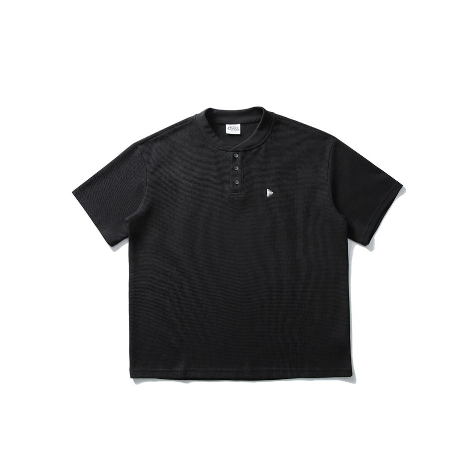 Black waffle-knit short-sleeve henley tee with band collar, button placket and small white chest logo, flat lay