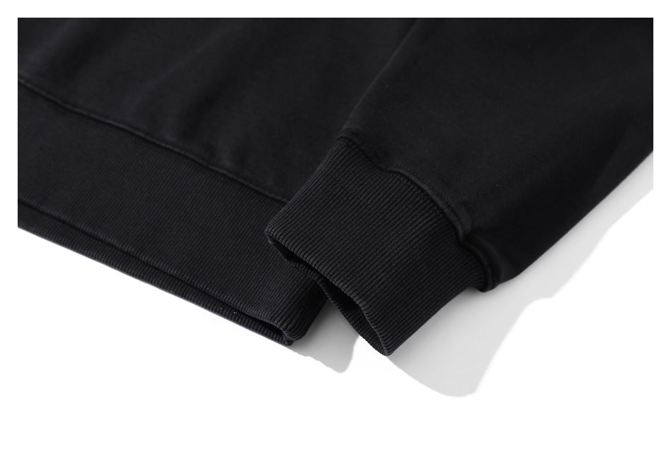 Close-up of a black garment's ribbed cuff beside its ribbed hem.
