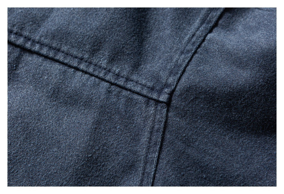 Close-up of dark blue denim with intersecting stitched seams and a curved fabric panel.