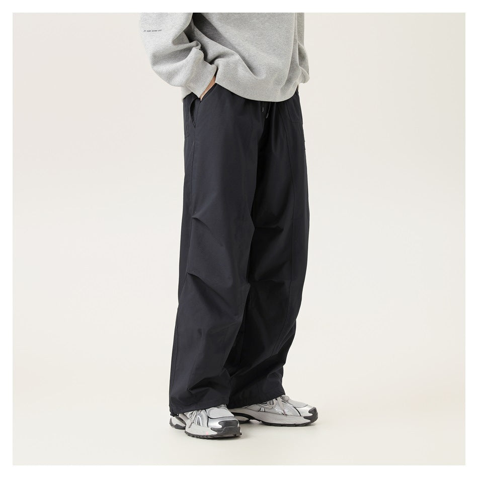Side view of a person wearing black-blue wide-leg pants with a gray sweatshirt and silver sneakers