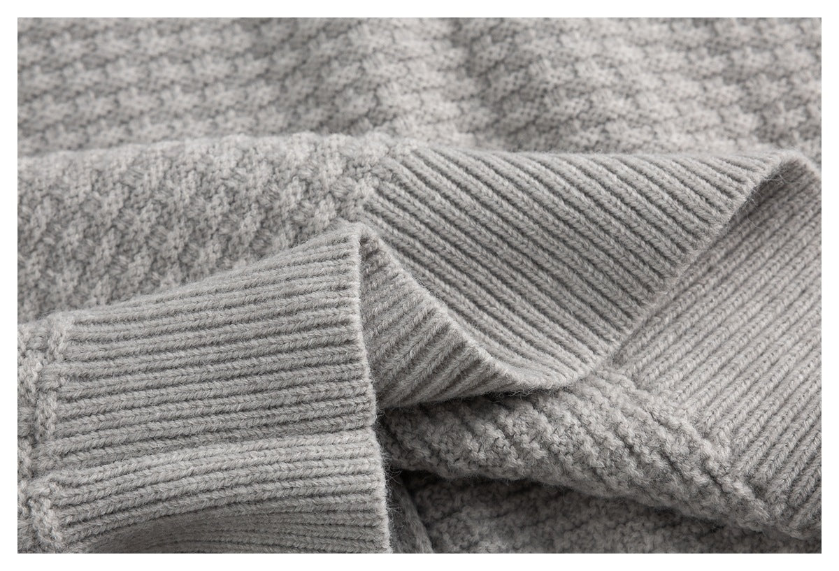 Close-up of a light gray sweater's ribbed cuff and textured knit fabric.