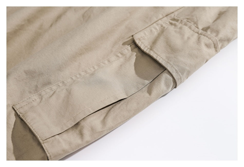 Close-up of a flap cargo pocket and stitching on beige pants.