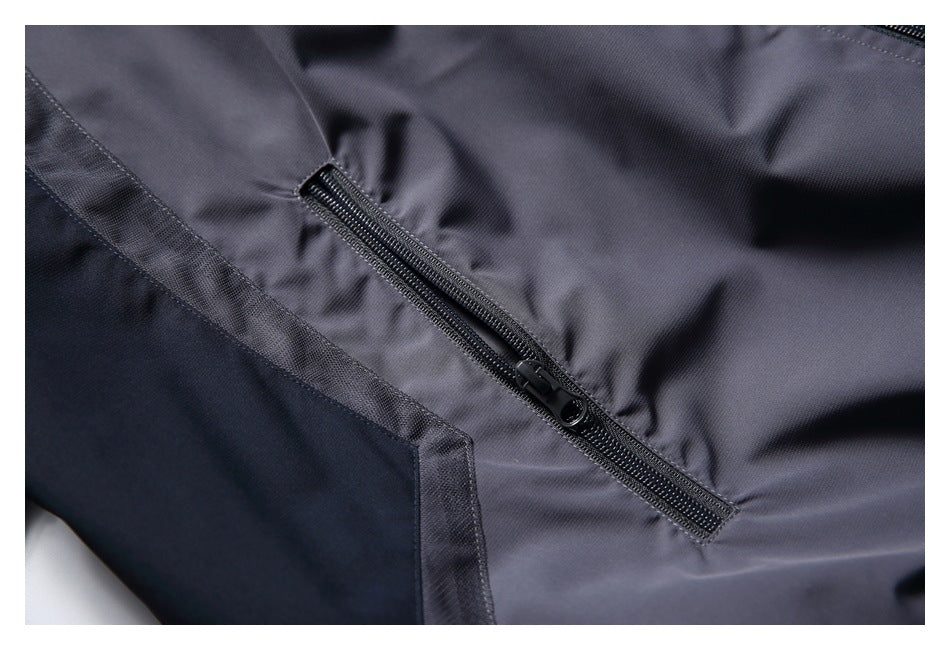 Close-up of a black zip pocket and dark panel seam on the charcoal-gray jacket.