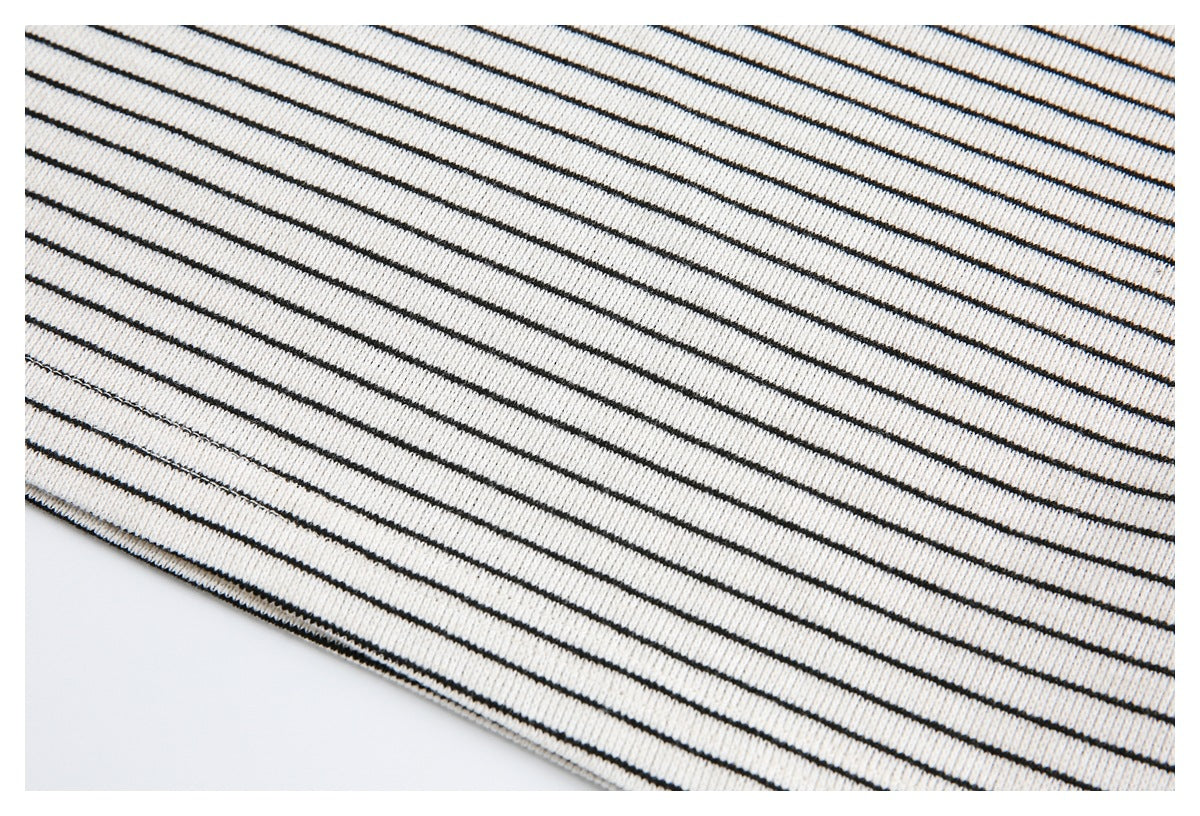 Close-up of cream knit fabric with thin black stripes and a finished diagonal edge.