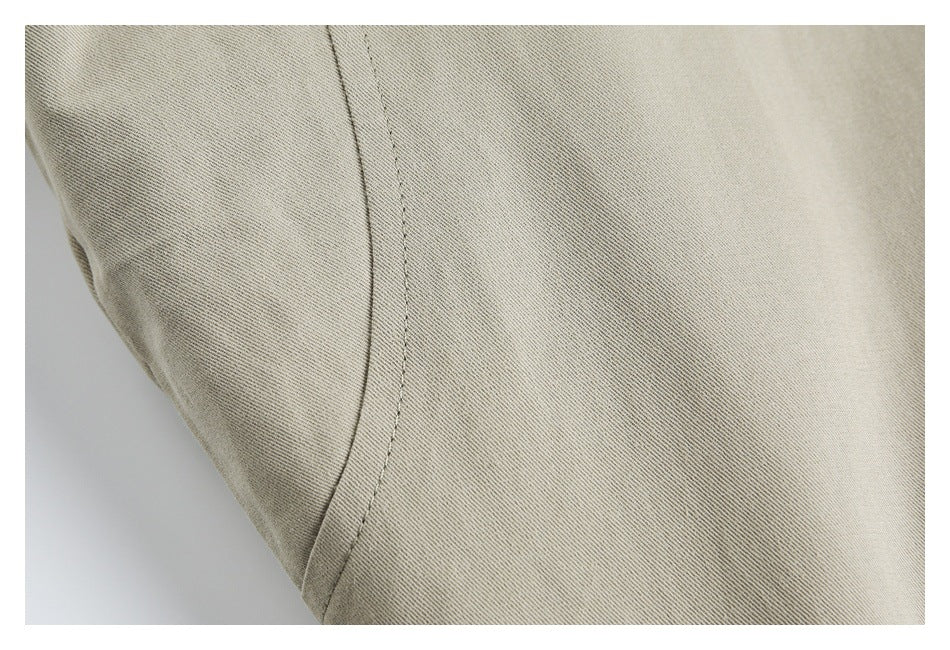 Close-up of light khaki fabric with a curved stitched seam.