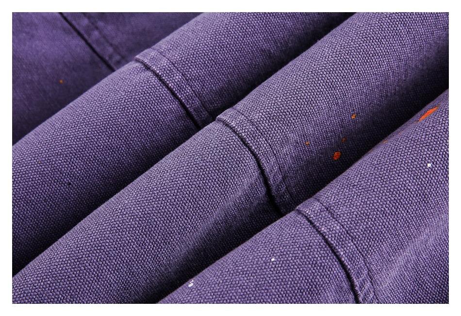 Close-up of purple jacket sleeves showing textured fabric, stitched seams, and small colored specks.