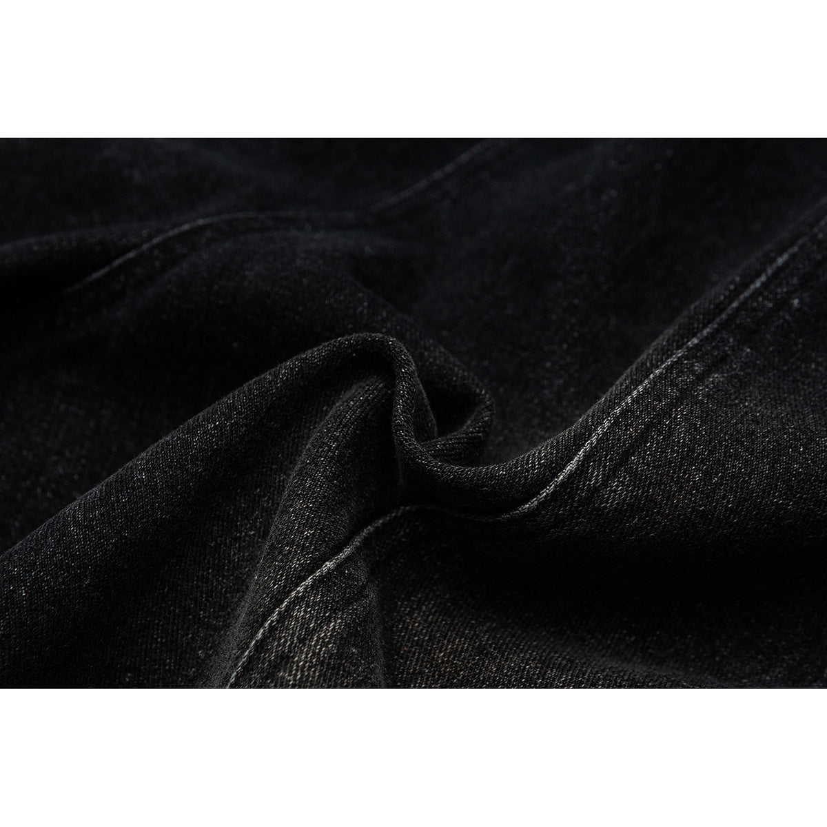 Close-up of black fabric folded to show its texture and stitched edge.