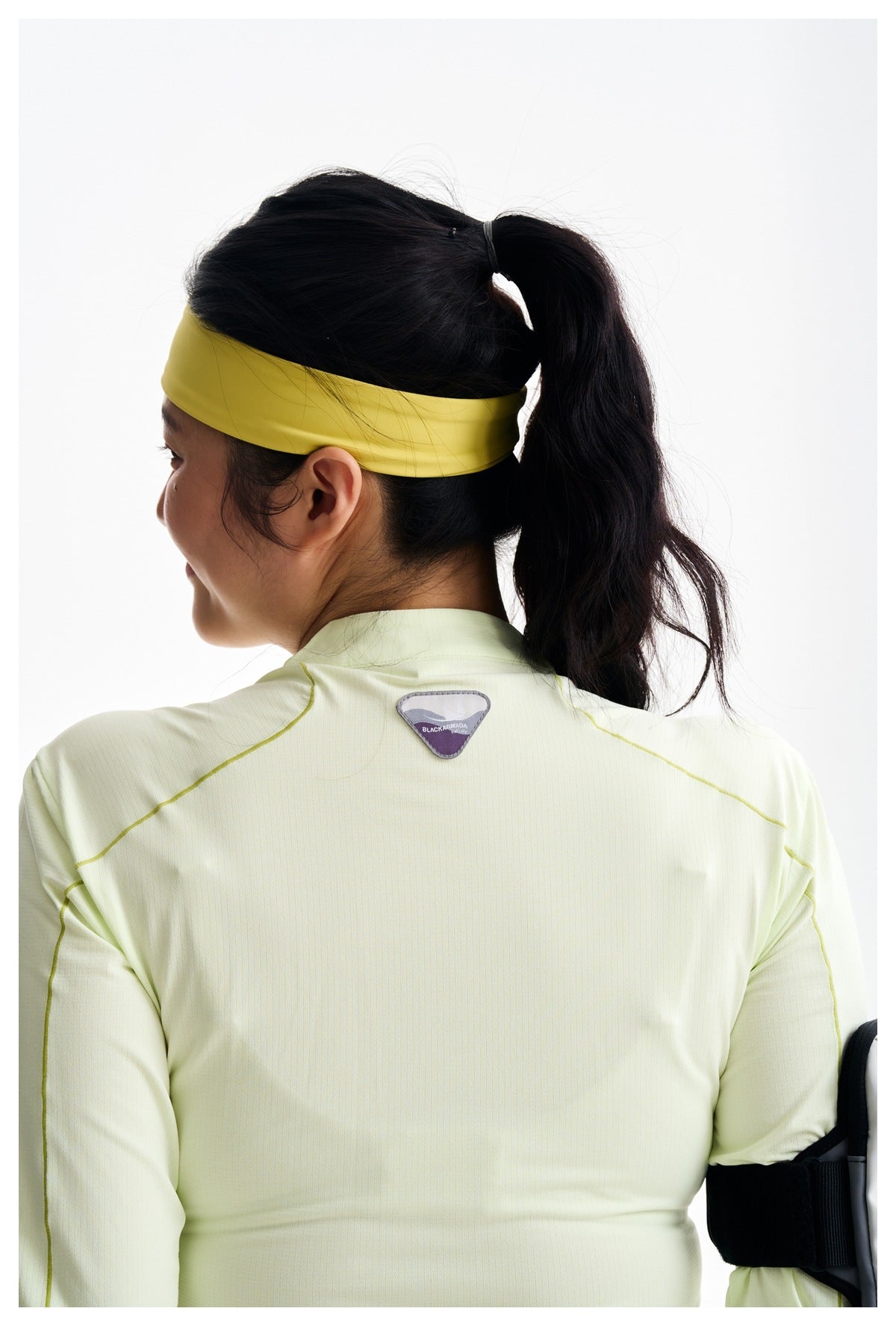Close back view of a pale yellow long-sleeve top with contrasting seams and a small triangular upper-back patch.