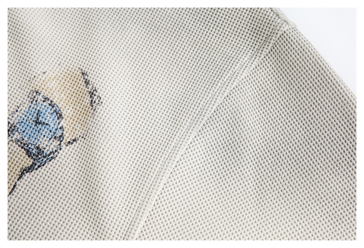 Close-up of cream textured knit fabric, a seam, and part of a printed illustration.