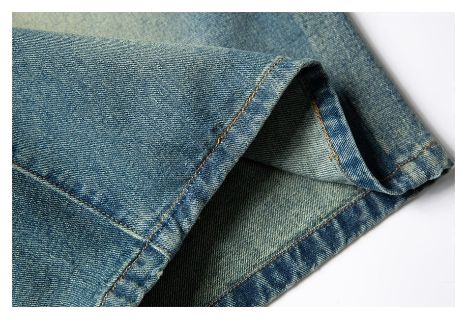 Close-up of a wide denim shorts hem, showing the folded edge, orange stitching, and inner fabric.