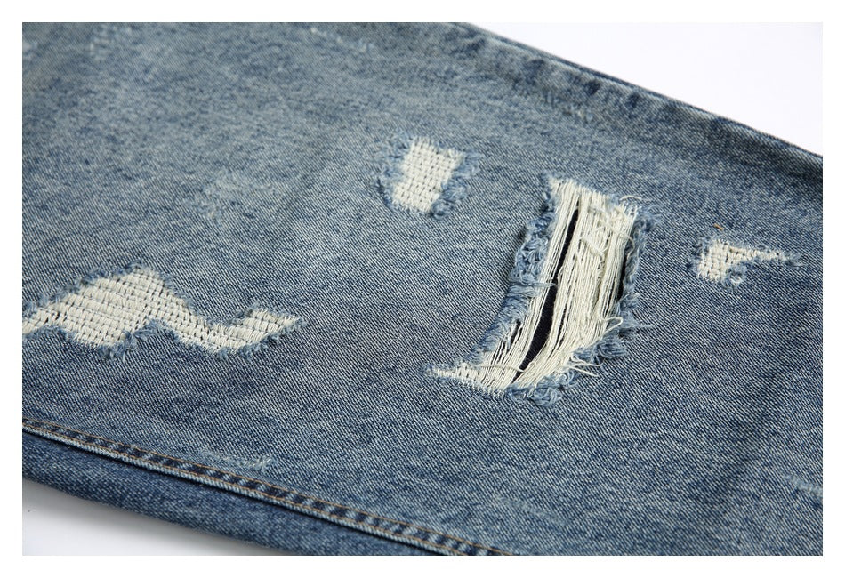 Close-up of blue denim with several white repaired and frayed distressed patches.