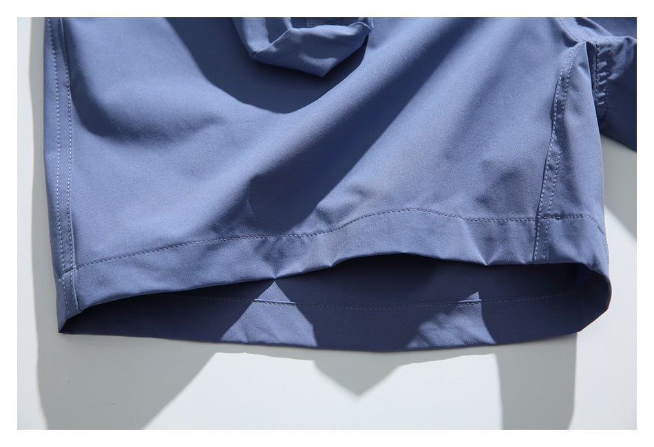 Close-up of the hem and stitching on blue shorts laid flat.