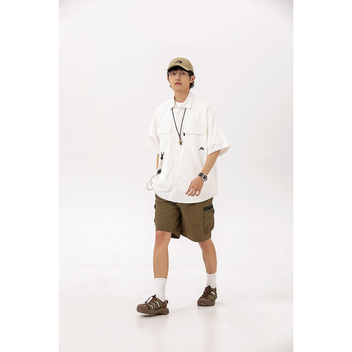 Model wearing an oversized white short-sleeve button-up shirt with chest pockets and brown cargo shorts.