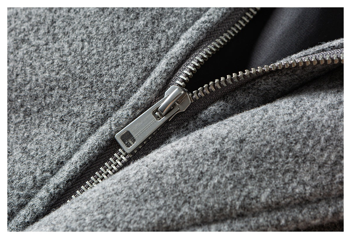 Close-up of an open metal zipper set into mottled gray fabric with dark lining visible.