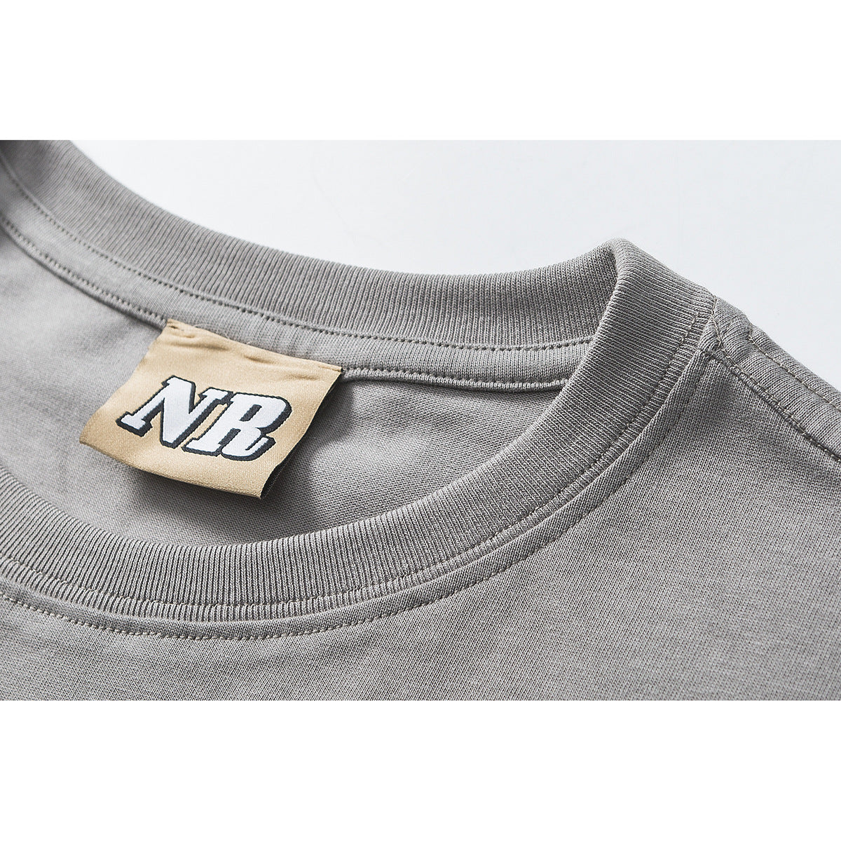 Close-up of a gray T-shirt's ribbed crew neckline and tan NB label.