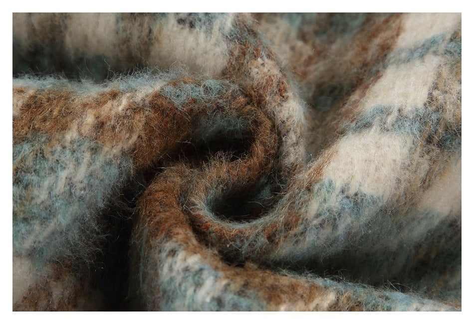 Close-up of folded fuzzy plaid fabric in brown, blue-gray, and cream tones.