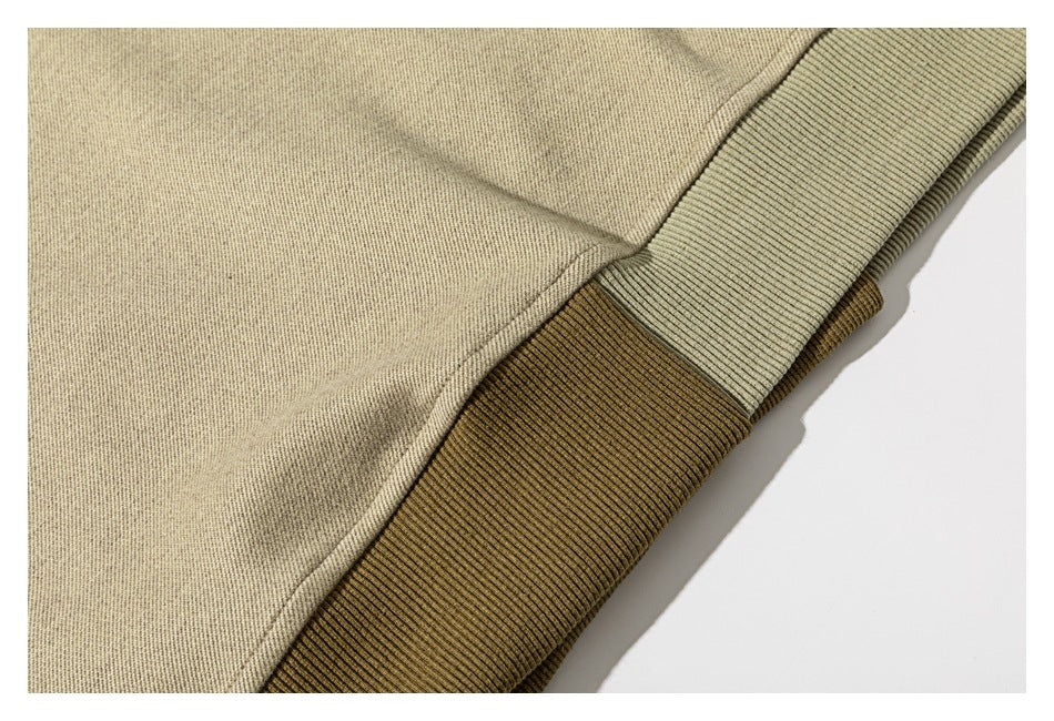 Close-up of a sweatshirt hem with contrasting olive and brown ribbed bands.