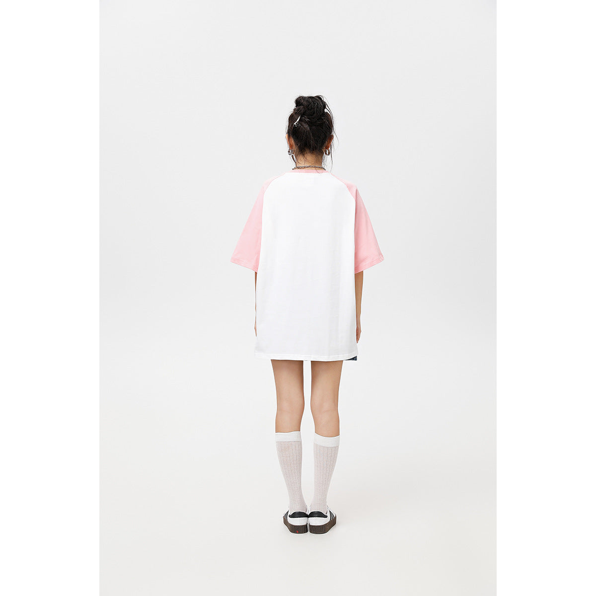 Back view of a model wearing an oversized white T-shirt with pink raglan sleeves.