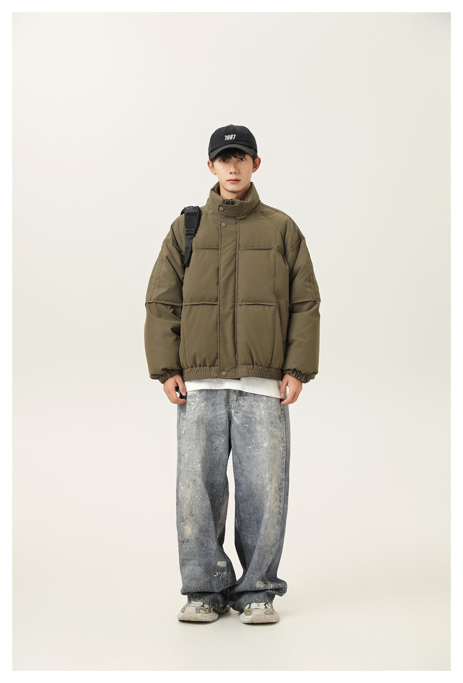 Full-length front view of a model wearing an olive green padded jacket with a high collar and elastic hem.