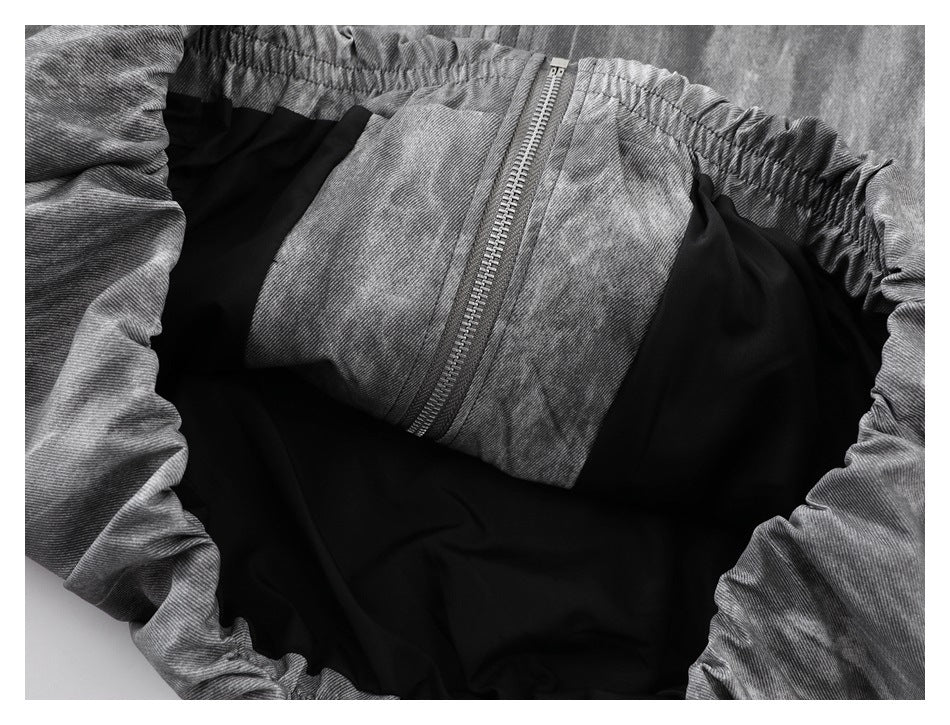 Close-up of gray acid-wash pants with an elastic waistband, zipper, and black interior lining.
