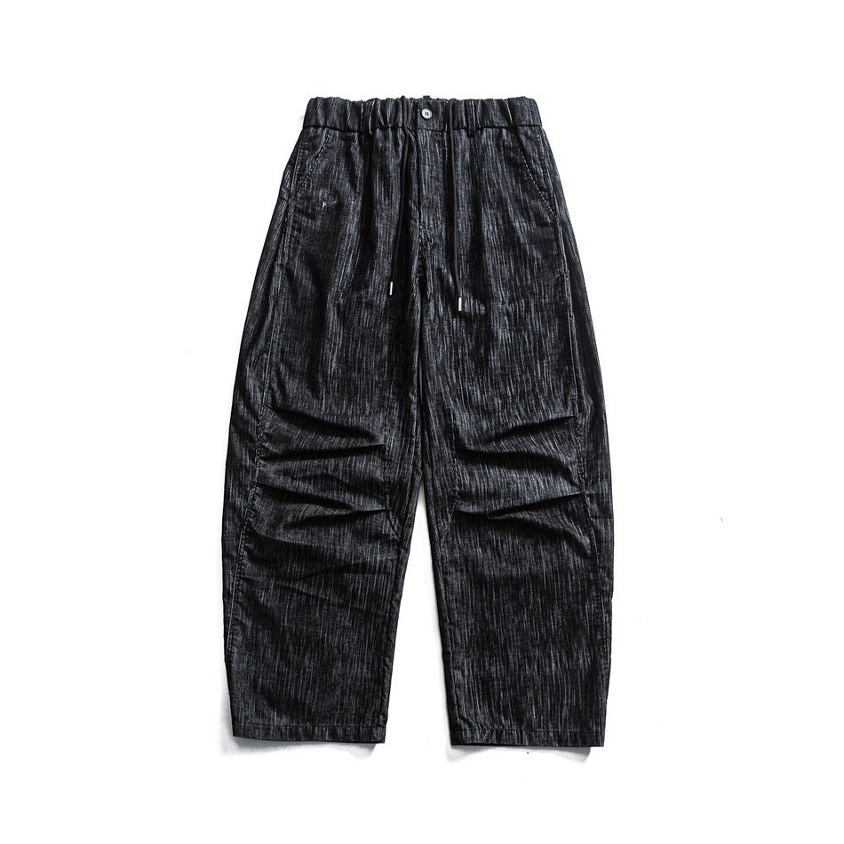 Black wide-leg drawstring pants with elastic waist, knee pleats and streaky washed texture, flat lay front view