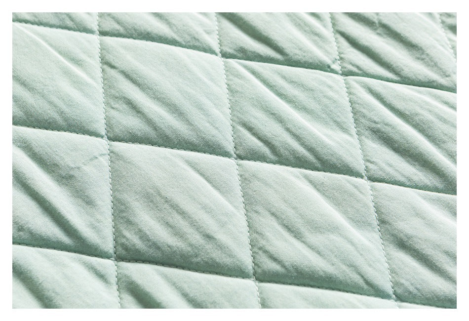 Close-up of pale mint fabric with large rectangular quilted stitching.