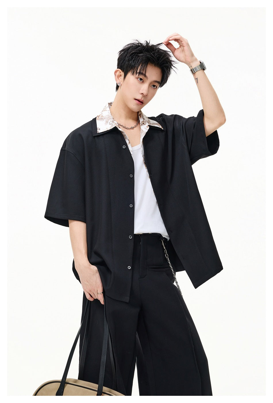 Model wearing an oversized black short-sleeve shirt with a contrasting floral collar and white tank, styled with black