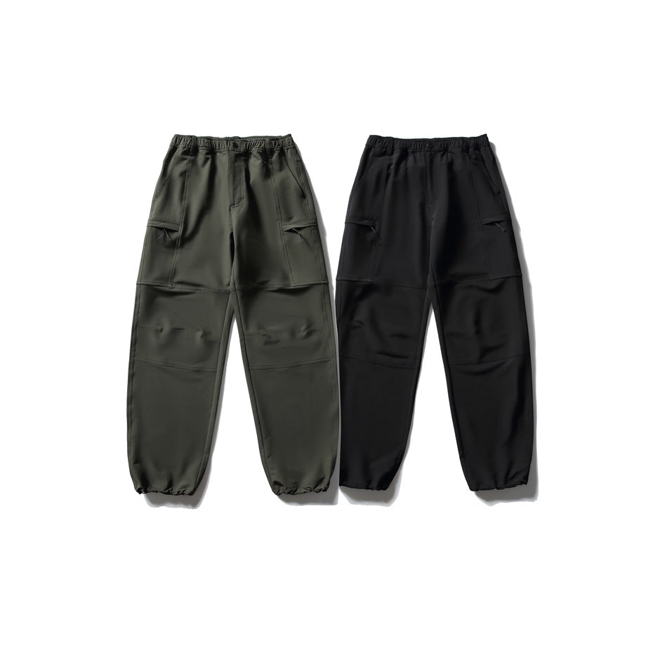 Two pairs of utility pants shown from the front in dark olive and black, with elastic cuffs and panel details.