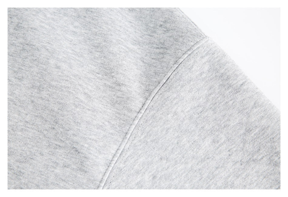 Close-up of a curved shoulder seam on light heather-gray sweatshirt fabric.